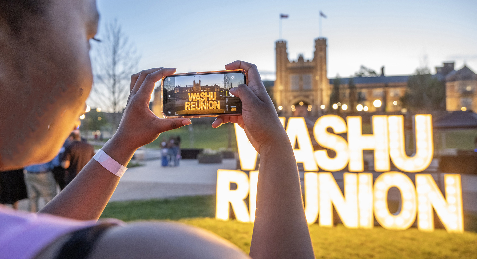 alum taking picture of WashU Reunion sign
