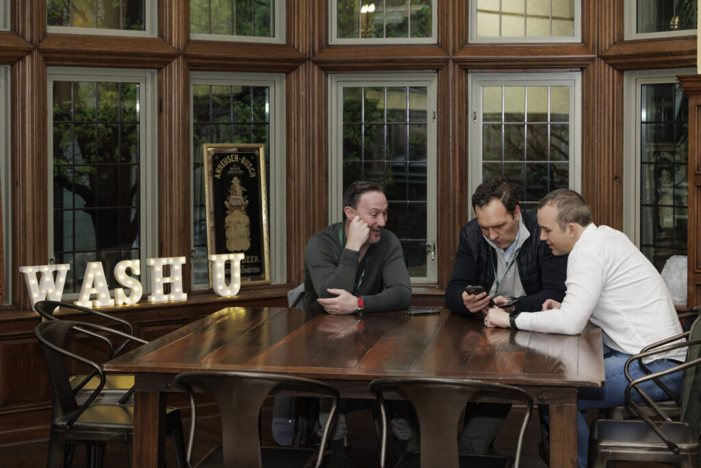 alums sitting next to WashU sign