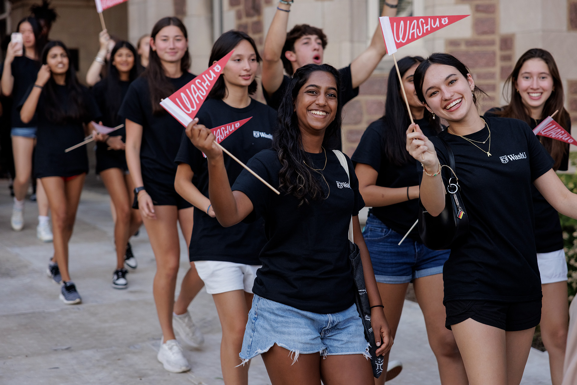 students holding WashU pennants
