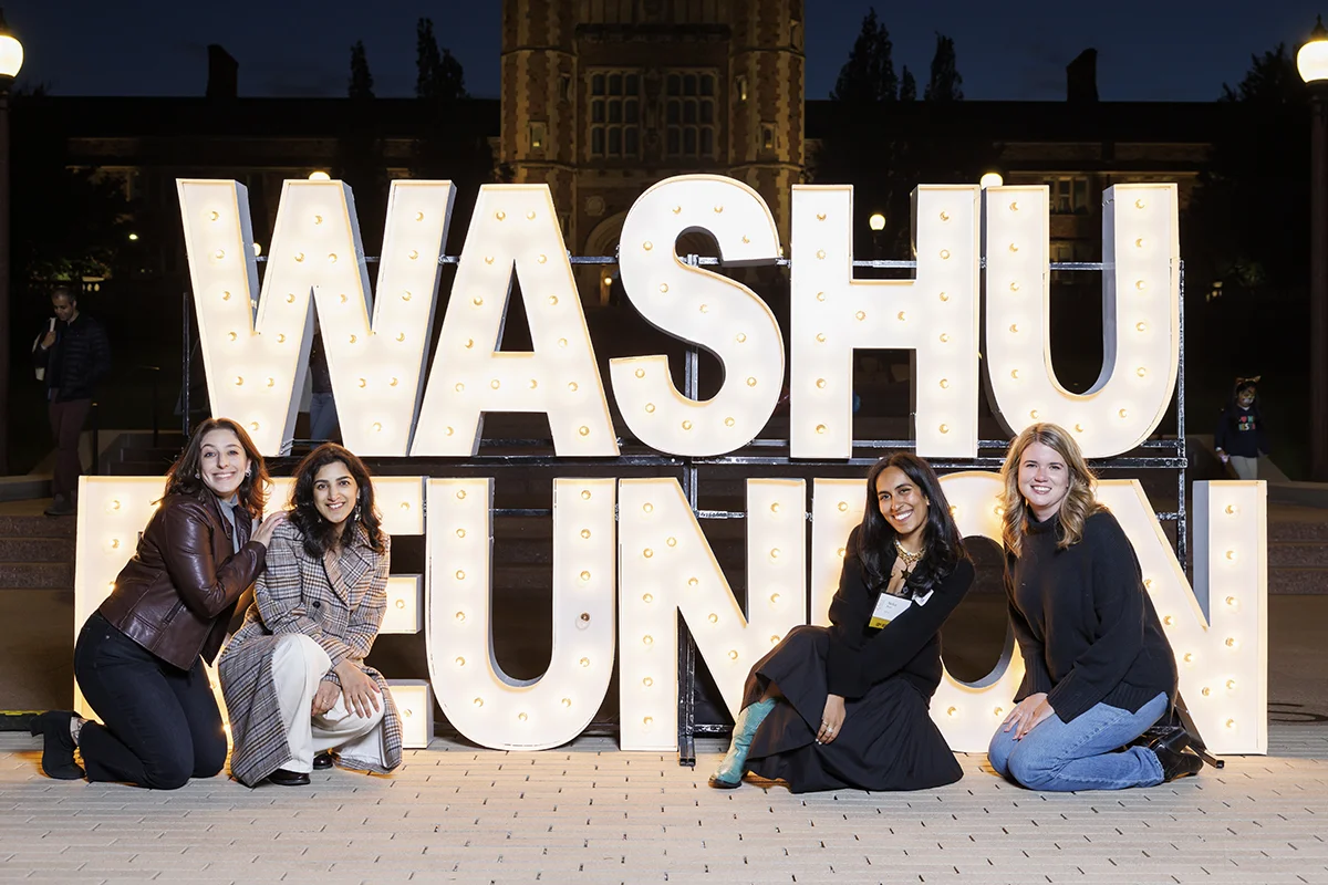 alumni pose in front of WashU Reunion sign