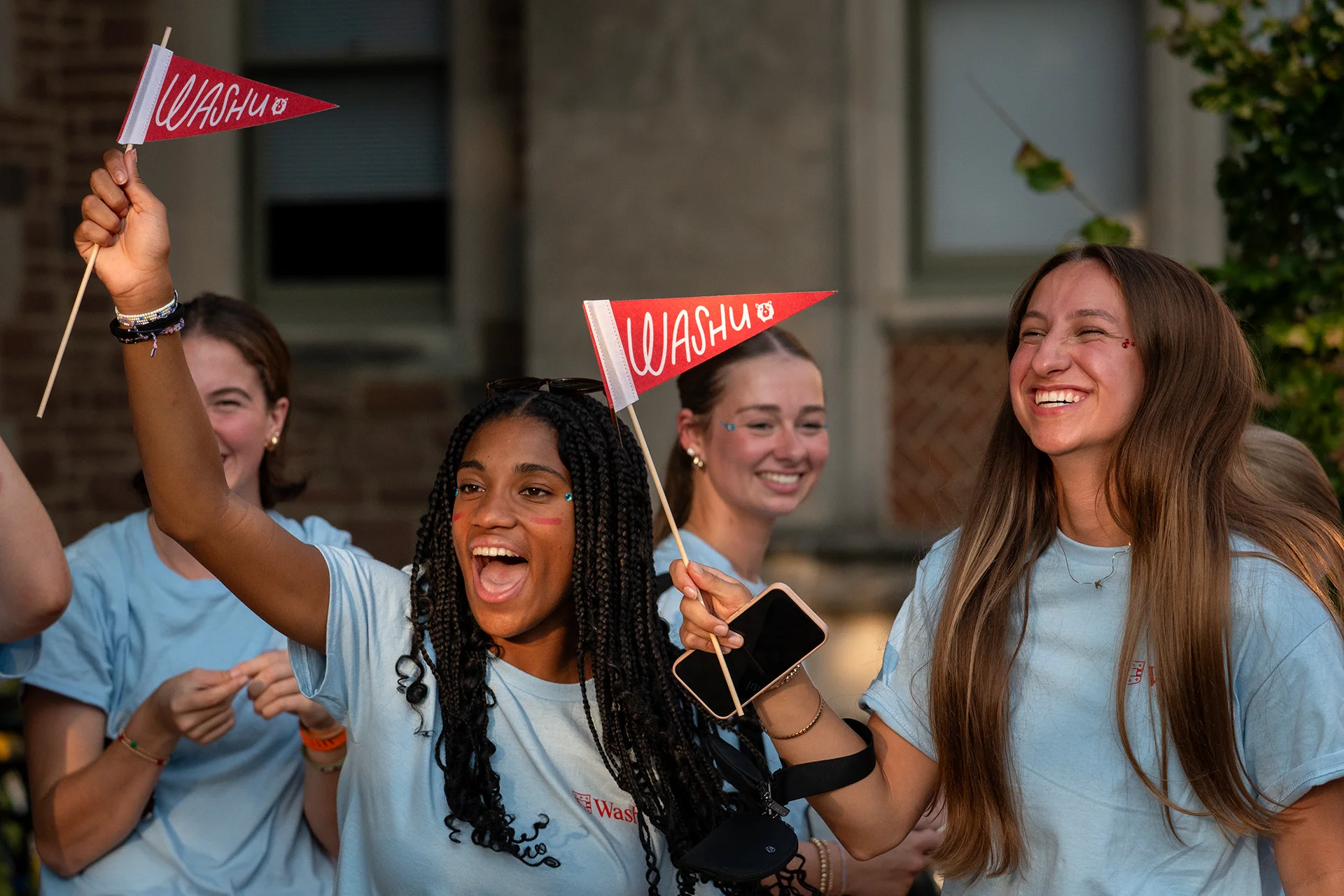group of students waving WashU pennants